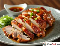  An exquisitely arranged image where slices of roast duck are neatly placed in the center of the plate, surrounded by sweet bean sauce, scallion shreds, cucumber strips, and thin pancakes, with a striking color contrast.