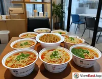 During office lunchtime, colleagues gather around a table, sharing Lanzhou Hand-Pulled Noodles delivered by takeout, enhancing their friendship.