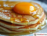 A close-up of the pancake roll, with the egg mixture slowly solidifying on the pancake, forming an enticing golden yellow.