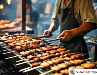 The barbecue master is busy in front of the grill, skillfully turning various ingredients to ensure each skewer is grilled to perfection.