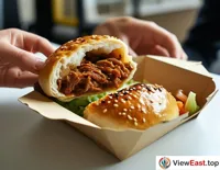 During lunchtime in the office, an employee is taking out a steaming Rou Jia Mo from a takeout box, ready to savor it.