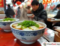  In a bustling traditional Chinese breakfast shop, a customer is enjoying a steaming bowl of tofu pudding, sprinkled with green scallions.