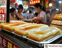 On a busy Guangdong street, a snack shop displays freshly made Cheong fun, drawing passersby for a quick tasty breakfast.