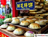 On a Yunnan snack street, shops advertise flower cakes, with tourists lining up to taste this Yunnan specialty.