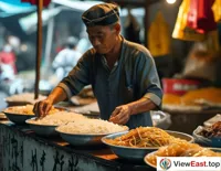 At a Guangxi village market, a vendor prepares a bowl of Guilin rice noodles full of color, aroma, and taste for a customer.