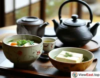 A bowl of tofu and vegetable soup at a Japanese restaurant, next to a pot of hot tea, adding a touch of Zen to the dining experience.