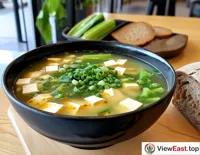 A refreshing bowl of tofu and vegetable soup in a gym's light food area, paired with a whole wheat bread, replenishing nutrients post-workout.